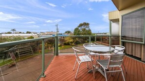 A balcony with a glass railing, a wooden deck, and a table with chairs. - Comfort Inn and Suites Lakes Entrance (Lakes Entrance)