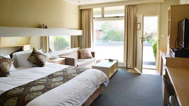 A hotel room with a bed, a desk, a chair, a television, and a view of the outdoors. - Comfort Inn and Suites Lakes Entrance (Lakes Entrance)