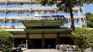 Un hôtel appelé HOTEL TZAREVETZ, doté d’une façade moderne, de nombreux balcons et d’un espace d’entrée couvert avec des sièges en plein air.