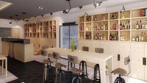Un espace bar avec des étagères en bois remplies de bouteilles, un comptoir et des tabourets de bar.