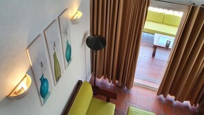A room with a yellow sofa, a small green ottoman, a floor lamp, and artwork on the wall. - Jonys Beach Resort (Boracay Island)