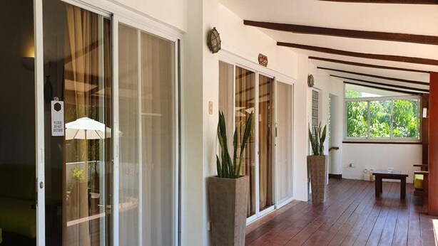 A hallway with sliding glass doors, potted plants, and a wooden floor. - Jonys Beach Resort (Boracay Island)