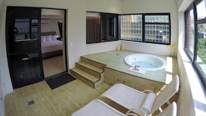A modern bathroom with a bathtub, a shower area, and a seating area with towels. - Royal Savassi Boutique Hotel (Belo Horizonte)