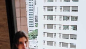 A person sitting by a window in a room with a view of a building. - Royal Savassi Boutique Hotel (Belo Horizonte)