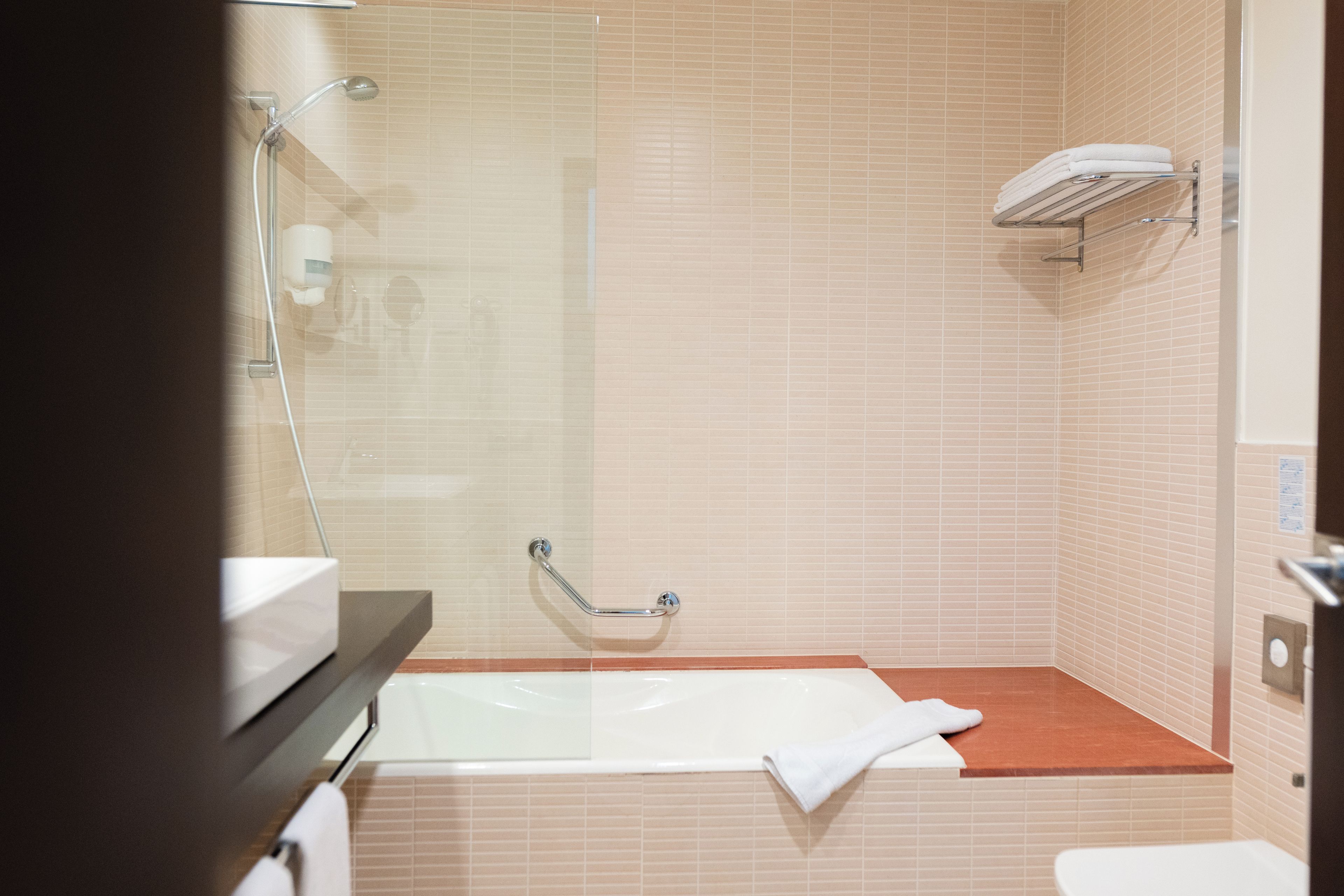 Ein Badezimmer mit Duschkabine aus Glas, einer weißen Badewanne und einem Handtuchhalter.