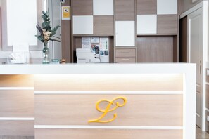 A reception desk with a wooden panel design, a glass vase with flowers, and a printer. - Loar Ferreries (Ferreries)