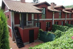 A multi-story building with a red facade and terracotta roof tiles.