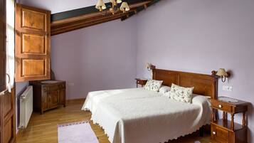 Un dormitorio con cama de madera, mesita de noche, cómoda y radiador.