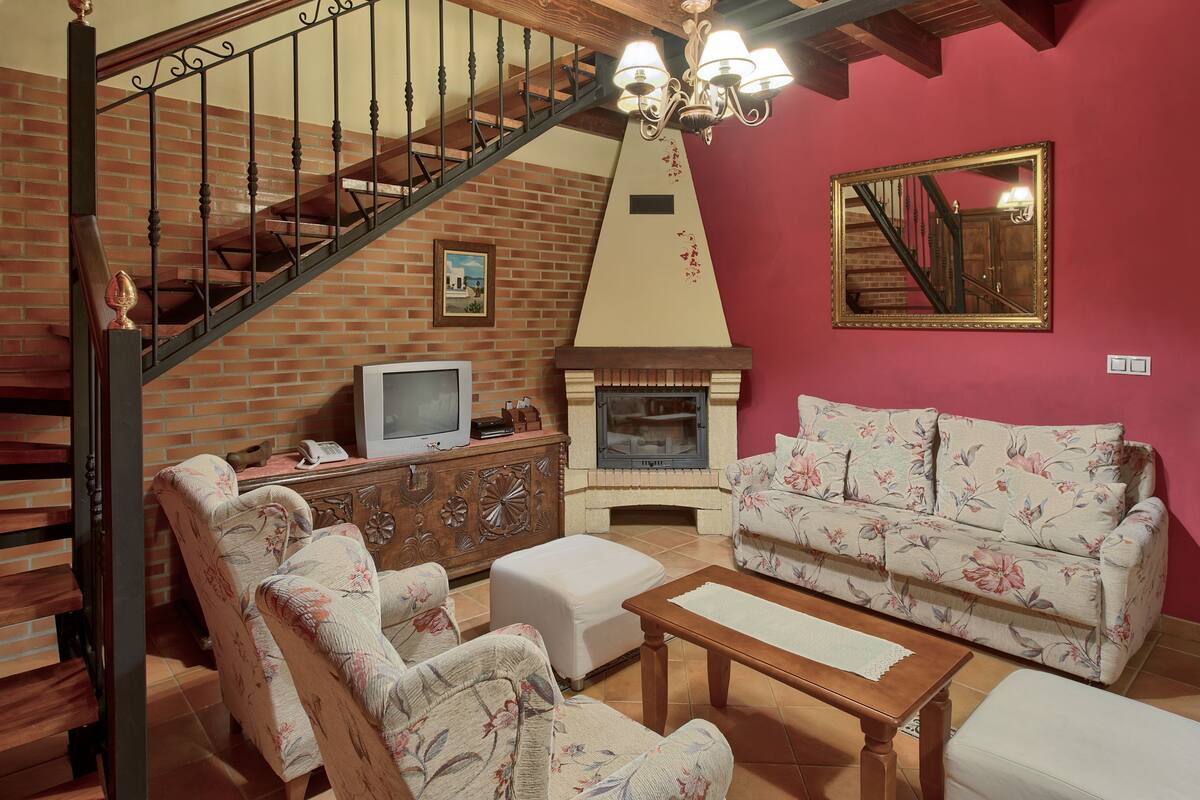 Uma sala de estar com lareira, sofá, televisão e escada.