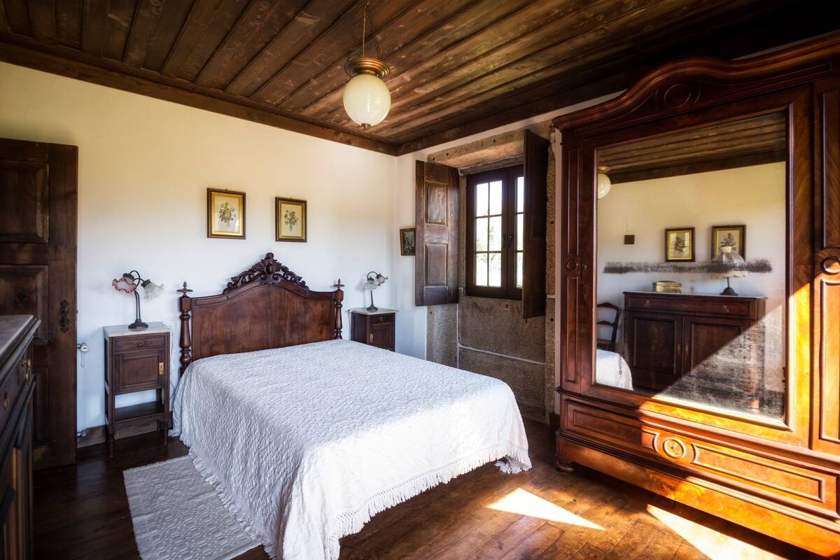 A traditional bedroom with a wooden bed, a large mirror, and a wooden ceiling.
