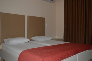 A bed with a red blanket, white pillows, and a headboard. - Triantafillas Apartments (Rhodes)