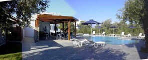 A pool area with lounge chairs, umbrellas, and a covered seating area. - Triantafillas Apartments (Rhodes)