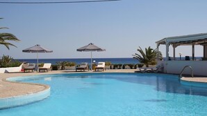 A swimming pool with lounge chairs and umbrellas, overlooking the sea. - Mediterranean Hotel (Karpathos)