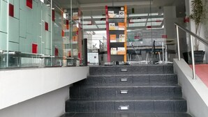 Een moderne trap met glazen leuningen en een metalen handrail, die naar een lager gelegen niveau leidt.