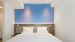 Een moderne hotelkamer met een groot bed, een houten hoofdeinde en een blauwe accentmuur.