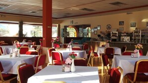 Un restaurante con varias mesas y sillas, una barra y cuadros en la pared.