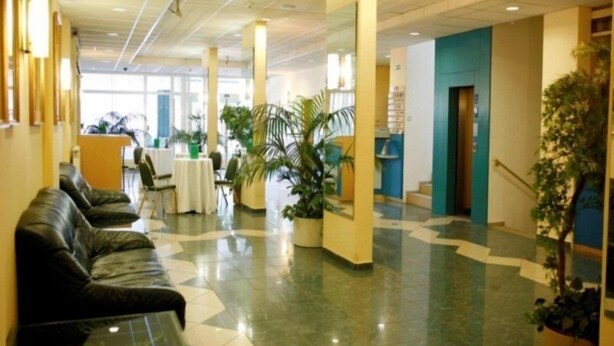 A hotel lobby with a check-in counter, seating area, and potted plants. - Bara (Budapest)