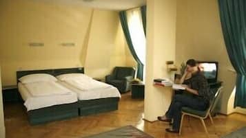 Una habitación de hotel con dos camas, un escritorio, una silla, un televisor y un ventanal con cortinas.