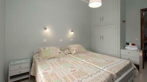 A bedroom with a bed, bedside tables, a wardrobe, and wall-mounted lights. - Villa Eleni (Corfu)