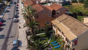 A coastal hotel with multiple buildings, a parking lot, and a view of the sea. - Villa Eleni (Corfu)