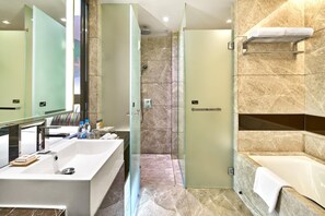 A modern bathroom with a large sink, a glass-enclosed shower, and a separate bathtub. - The Royal Garden Kowloon East (Sai Kung)