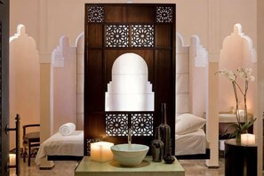 A spa room with a large arched mirror, a bowl, candles, and a decorative wall panel. - Sofitel Rabat Jardin des Roses (Rabat)