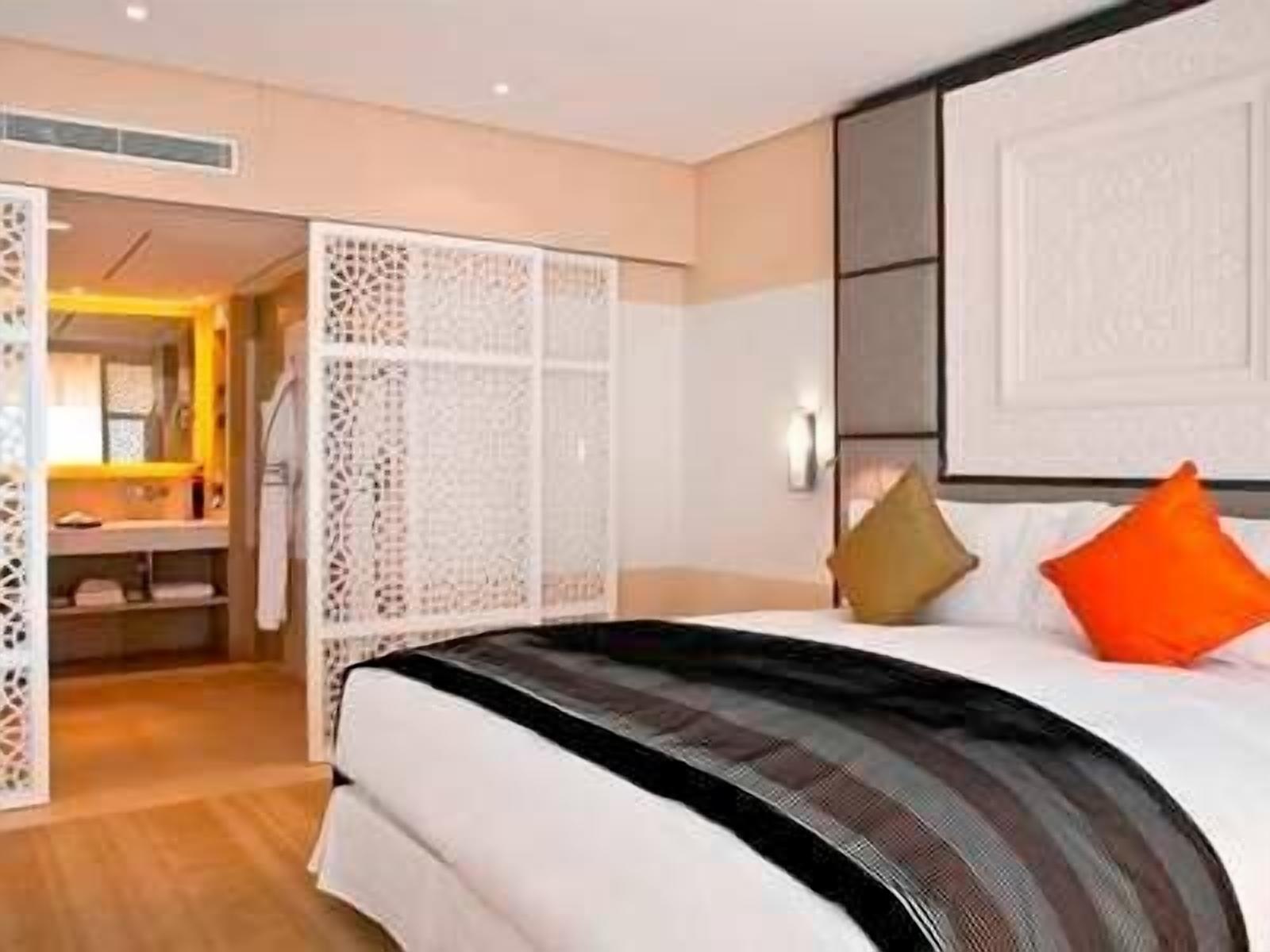 A hotel room with a bed, a bedside table, a mirror, and a wardrobe.
