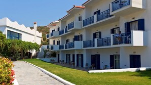 Un hôtel à plusieurs étages doté de balcons, d’un chemin en pierre et d’une pelouse bien entretenue.