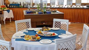 A buffet setup with various dishes, a coffee machine, and a view of the kitchen in the background.