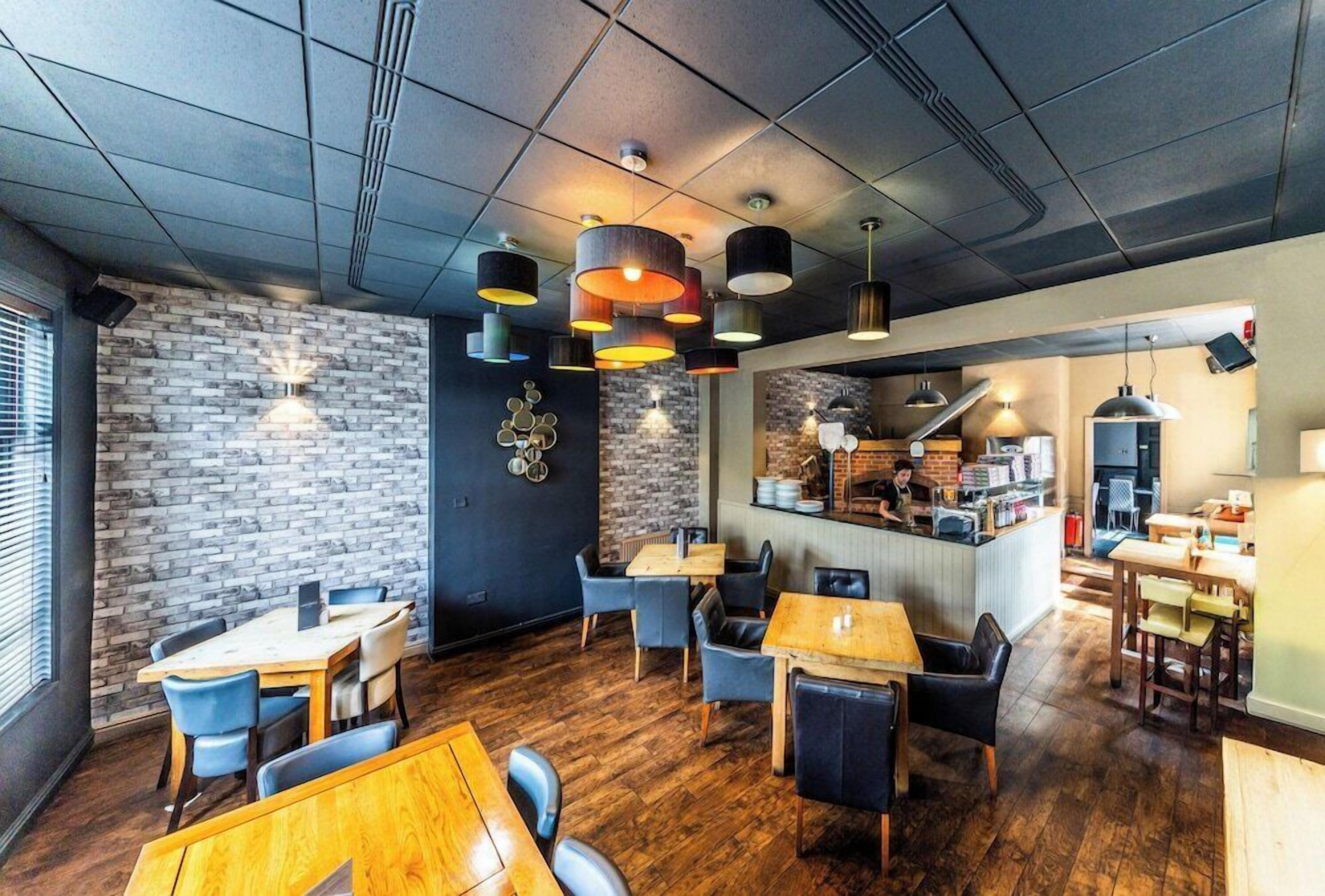 A modern restaurant with brick walls, wooden flooring, and multiple dining areas with tables and chairs.