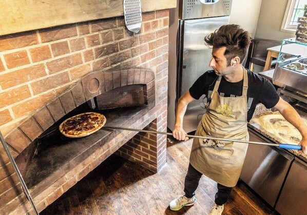 Une personne préparant une pizza dans un four en briques.