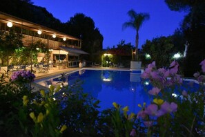 A pool area with lounge chairs and a building with outdoor seating. - Lydias Beach (Lefkada)