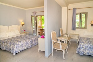 A hotel room with two beds, a small desk, a chair, and a window with curtains. - Efrosini Village (Kefalonia)