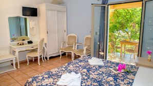 A hotel room with a bed, a desk, two chairs, a mirror, and a television. - Efrosini Village (Kefalonia)