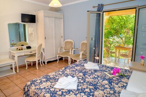 A hotel room with a bed, a desk, two chairs, a mirror, and a television. - Efrosini Village (Kefalonia)