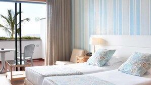 A hotel room with two beds, a balcony with a table and chairs, and a view of palm trees. - Quinta da Penha de Franca (Funchal)