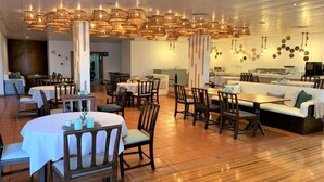 A restaurant with round tables, wooden chairs, and hanging wicker chandeliers. - Quinta da Penha de Franca (Funchal)