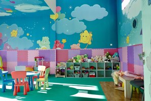 Ein Kinderzimmer mit bunten Möbeln, einer Wandmalerei und Regalen.