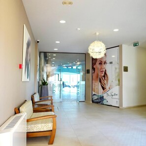 Un espace d’accueil comprenant un coin salon, une grande affiche et un luminaire au plafond.