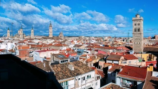 Paesaggio urbano con numerosi edifici, una torre imponente e cielo sereno.