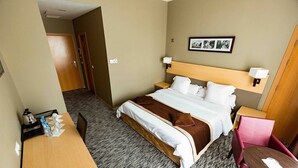 A hotel room with a bed, bedside tables, a desk, a chair, and a framed photo on the wall. - Hotel Les Zianides (Tlemcen)