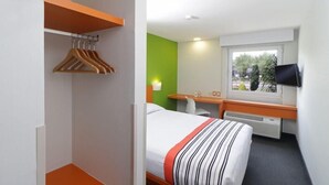 Habitación de hotel con cama, escritorio, silla, televisor y ventana.