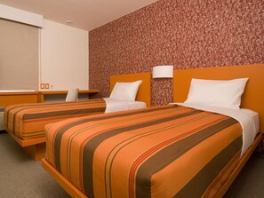Habitación de hotel con dos camas, un escritorio y un papel tapiz estampado.