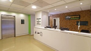 Mostrador de recepción con el logotipo de CityExpress Junior, zona de recepción y pared verde.