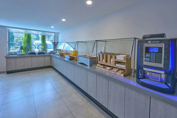 A modern cafe with a self-service coffee machine, a glass partition, and a view of the street outside.