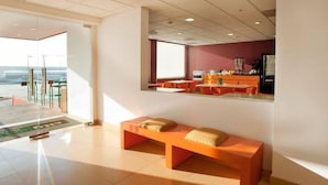 Un moderno vestíbulo de hotel con un banco, una recepción y vistas al exterior.