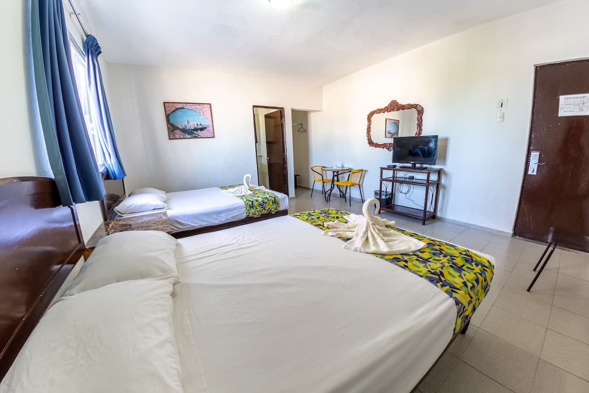 Une chambre d’hôtel avec deux lits, une télévision, un bureau avec une chaise et une porte.