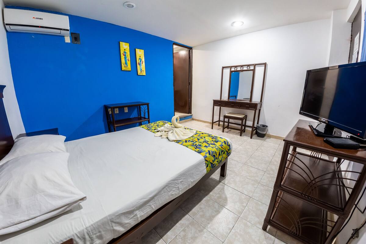 Une chambre d’hôtel équipée d’un lit, d’un bureau, d’une télévision et d’une armoire.