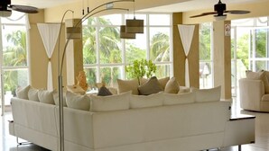 Ein modernes Wohnzimmer mit einem weißen Sofa, einer Stehlampe und großen Fenstern mit Vorhängen.