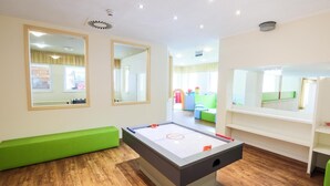 Una habitación con mesa de billar, asientos verdes, espejos y suelo de madera.